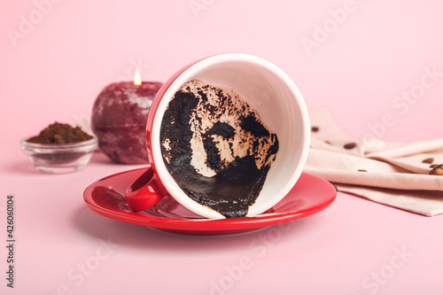 Cup with spent coffee grounds for fortune telling on color background photo