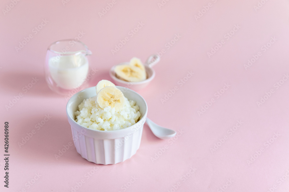 Rice porridge on vegetable milk with banana slices on a pink minimal background. Diet healthy Breakfast Rice porridge on vegetable milk with banana slices on a pink minimal background. Diet healthy Breakfast