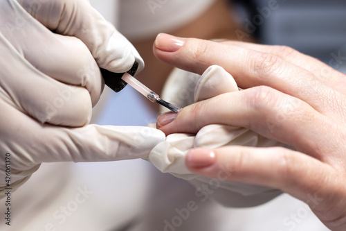 Manicure coating of nails on women's hands with gel polish in a beauty salon by a specialist. Close-up. Space for text