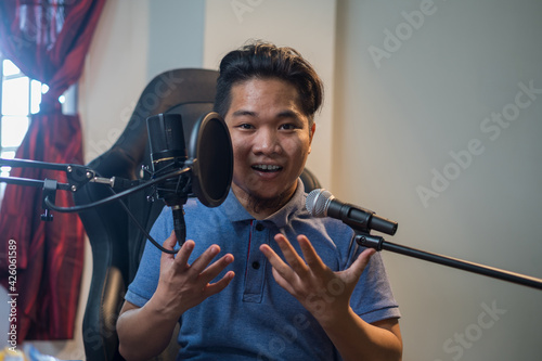 Portrait of young Asian man  with two microphone for singing or voice over or streamer with happy face. Selective focus. 
