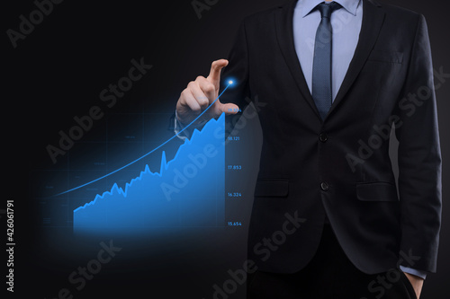 Business man holding holographic graphs and stock market statistics gain profits. Concept of growth planning and business strategy. Display of good economy form digital screen.