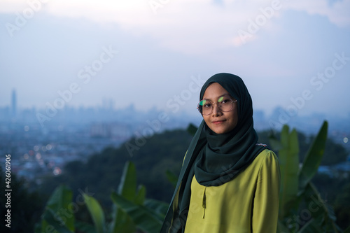 Portrait of young Asian woman during sunset, blue hour at hill view point, Bukit Ampang near Kuala Lumpur. Blurred background