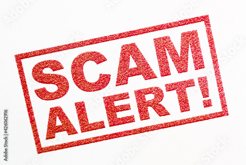 scam alert - red text stamp on white background photo