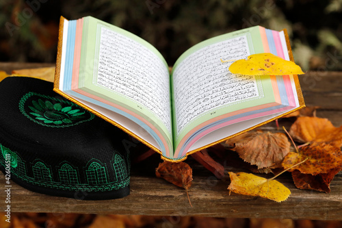An open Holy Quran on wood stand and a kufi, France