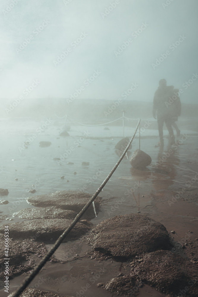 Obraz premium People walking through the cloud of steam from the erupted geyser. 