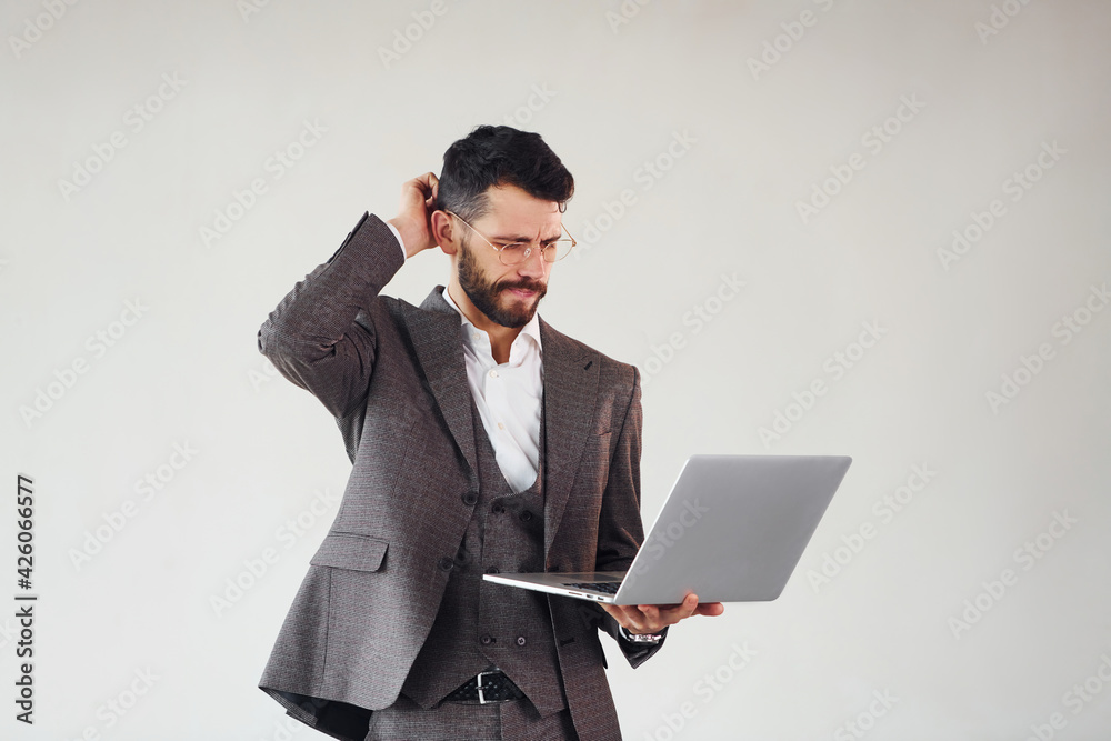 With laptop in hands. Young stylish businessman in suit indoors. Conception of success With laptop in hands. Young stylish businessman in suit indoors. Conception of success