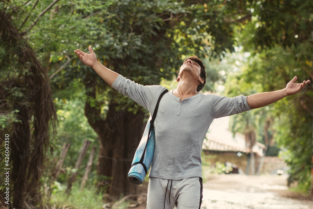 Latino young man spreading arms for breath and walking through forest Latino young man spreading arms for breath and walking through forest