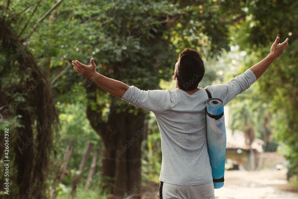 Latino young man spreading arms for breath and walking through forest Latino young man spreading arms for breath and walking through forest