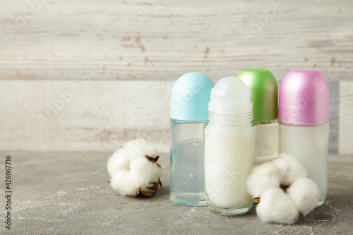 Different deodorants with cotton on light background with copy space.