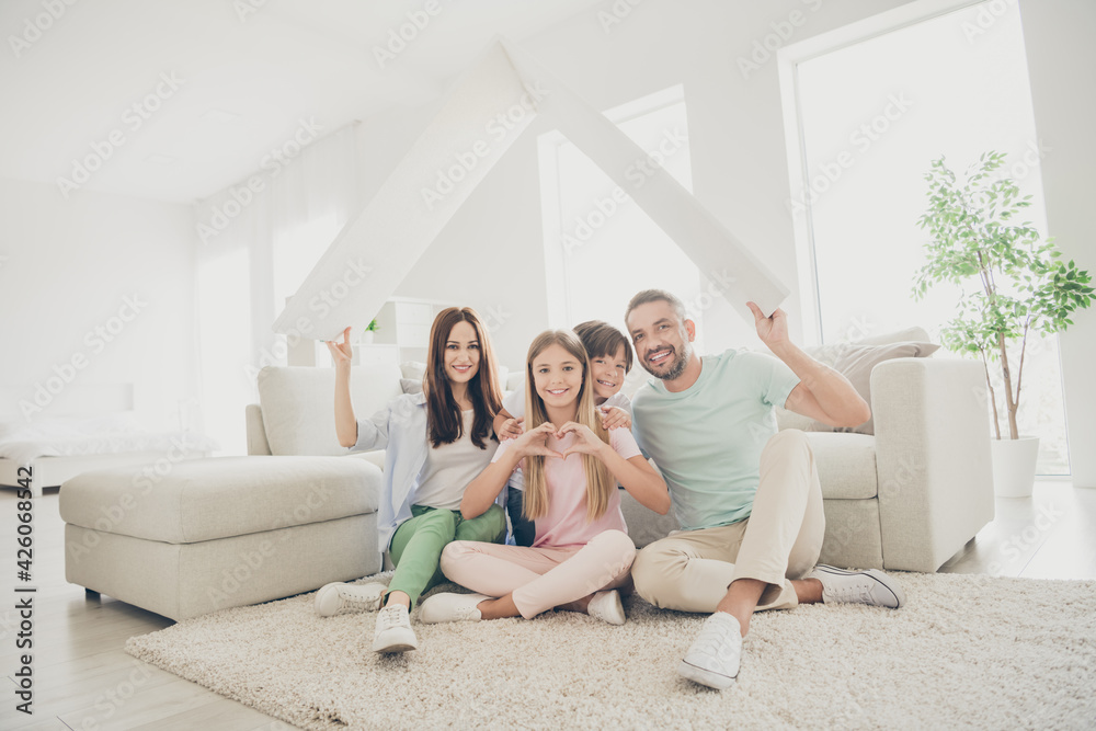 Full size photo of optimistic family mom dad two kids show home heart sit on floor wear t-shirts trousers at home