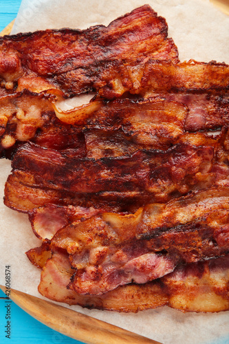 Bacon fried slices on cutting board on blue background. Top view