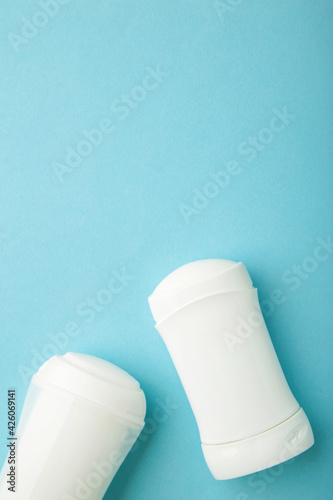 White antiperspirant deodorant on blue background. Skin care concept. copy space, top view