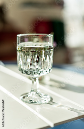 glass of mineral water close-up on white table in sunlight, healthy lifestyle, drink, vertical, soft focus