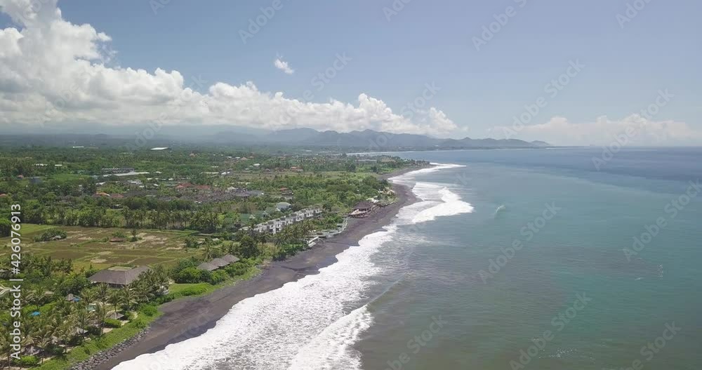 Aerial view, tropical resorts on Bali island, black sand beach, ocean waves and skyline on sunny summer day, panoramic drone shot Aerial view, tropical resorts on Bali island, black sand beach, ocean waves and skyline on sunny summer day, panoramic drone shot