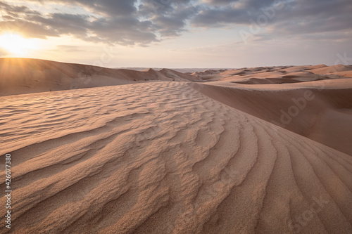 Sand dunes at sunset in the Wahiba Sands desert with clouds in the sky, Oman, Middle East photo