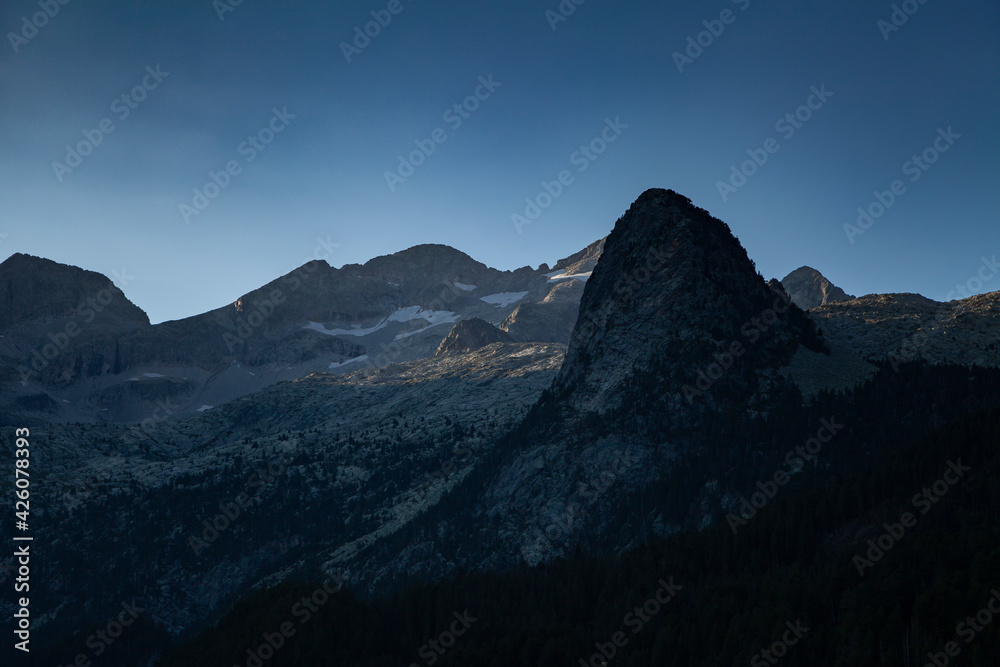 First light of dawn over the solitary mountains in summer, under a clean and huge blue sky, Aragonese Pyrenees, provincia de Huesca, Posets-Maladeta Natural Park.