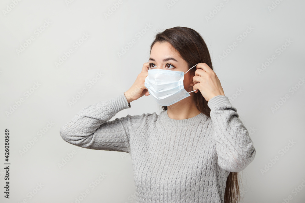 Young woman wearing medical mask, white background. Young woman wearing medical mask, white background.