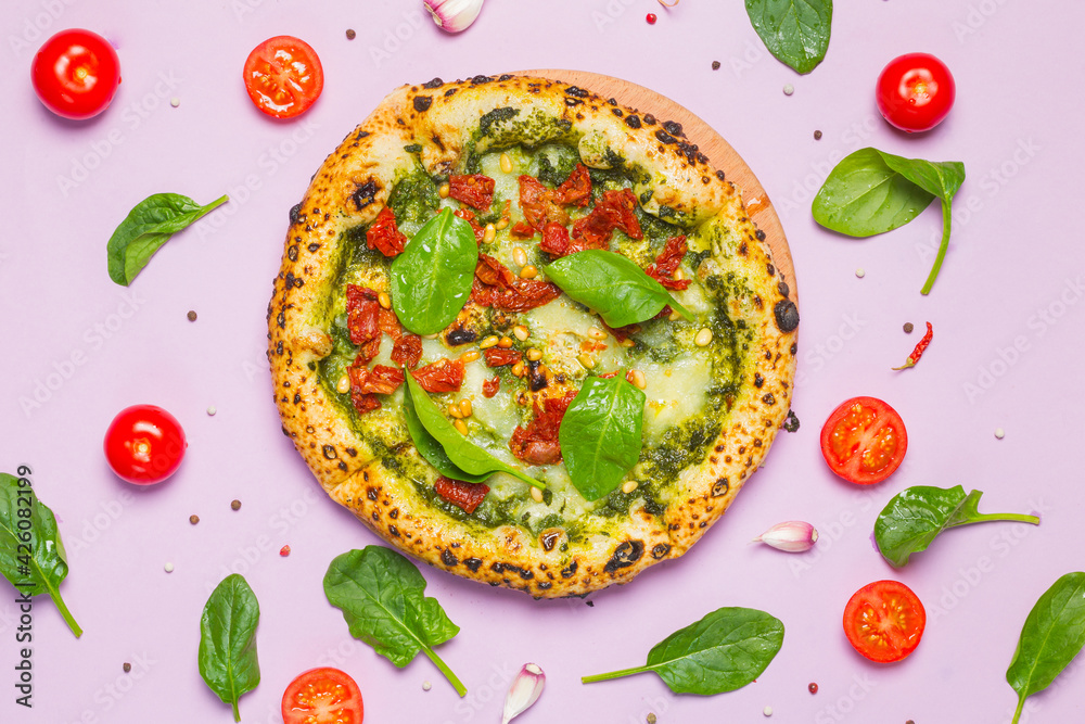 Pizza marinara bianca with pesto sauce, mozzarella, dried tomatoes, spinach and pine nuts. Close-up on a lilac background, overhead Pizza marinara bianca with pesto sauce, mozzarella, dried tomatoes, spinach and pine nuts. Close-up on a lilac background, overhead
