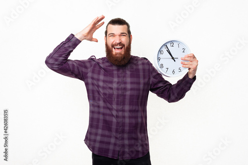 Photo of frustrated man holding wall clock and gesturing