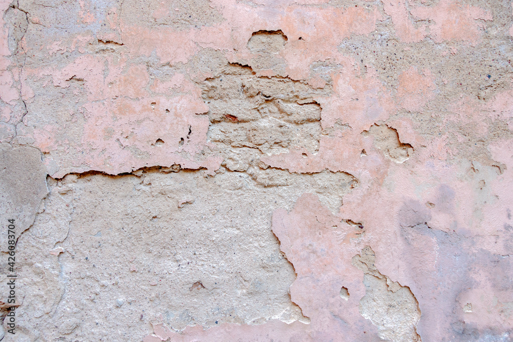 Old weathered painted wall background texture. White grey pink dirty peeled plaster wall with falling off flakes of paint