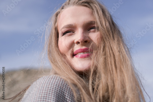 Beauty portrait of a young blond girl in a vintage dress. She is posing on a sandy landscape.