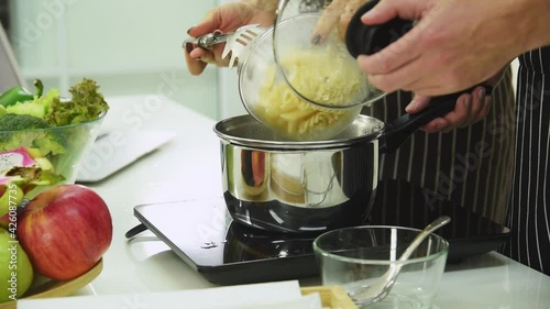 Man and woman couple in casual outfit preparing raw pasta for making healthy food in modern kitchen