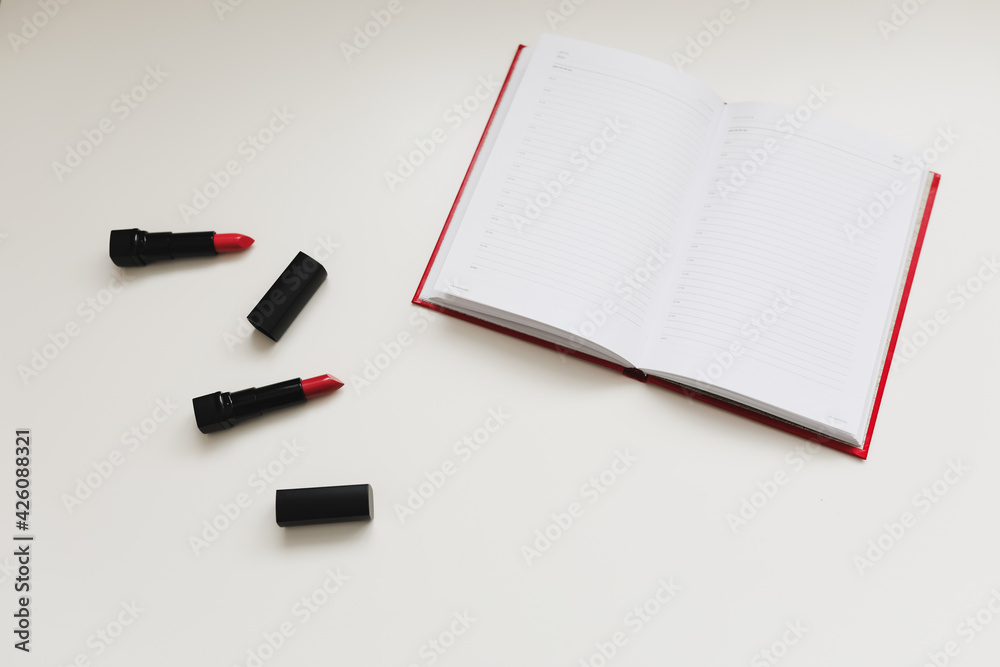 open notebook with cosmetics, accessories on white background. Minimal home workspace desk table. Flat lay, top view, mockup with copy space