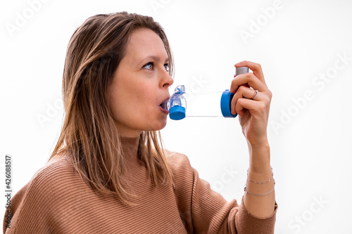 Young women taking asthma medication with an inhaler and spacer photo