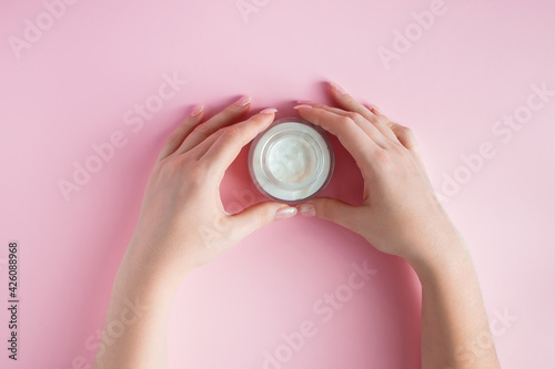 Fototapeta Naklejka Na Ścianę i Meble -  Nourishing cream and beautiful female hands on pink background. Skin care concept. Image for advertising and design.
