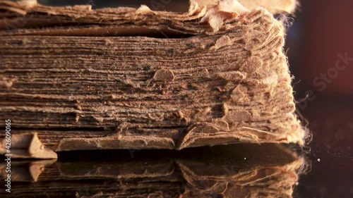 Time and knowledge concept, An eye glass specs kept in front of a really old torn and partially damaged religious scripture book. Extreme macro close up shot of an old vintage book