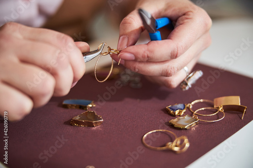 Skilled Caucasian female jeweler creating an earring photo