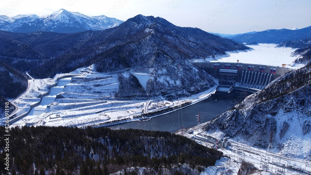 Aerial view over Sayano-Shushenskaya hydroelectric station dam in winter. A sign on the dam means “Russia”