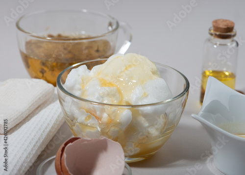 Egg White Face Mask ingredients. Whipped egg white, almond oil, honey, chamomile tea. Homemade cosmetic.
