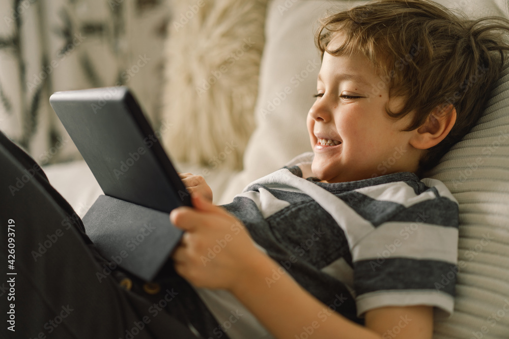 Little Boy with a tablet in the room. The boy play game on the tablet. Technology concept. Little Boy with a tablet in the room. The boy play game on the tablet. Technology concept.