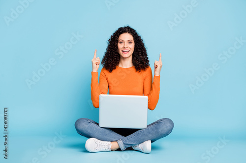 Portrait of nice trendy cheery girl sitting in lotus pose using laptop demonstrating up tips feedback copy space isolated bright blue color background © deagreez