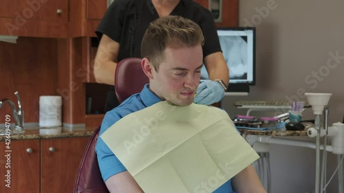 Dental Hygienist Places Dental Bib on Caucasian Man Patient photo