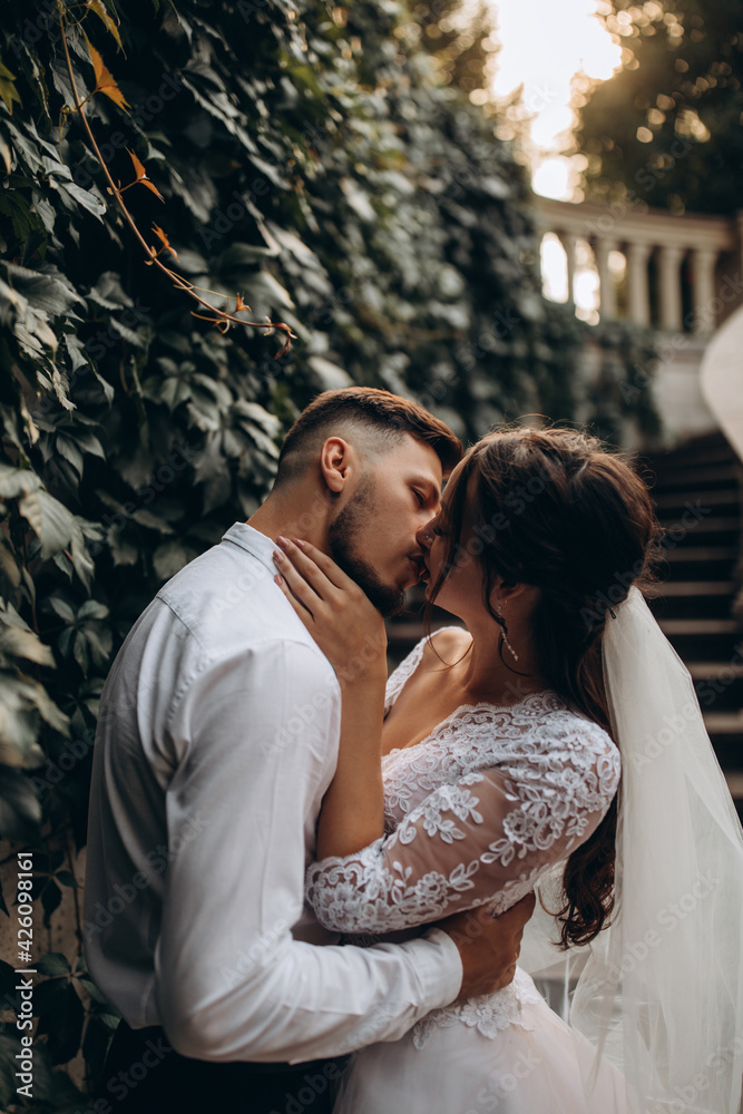 Walk of the newlyweds near the stone mansion. Warm summer evening. Portrait of the bride and groom. Evening photo session. Walk of the newlyweds near the stone mansion. Warm summer evening. Portrait of the bride and groom. Evening photo session.