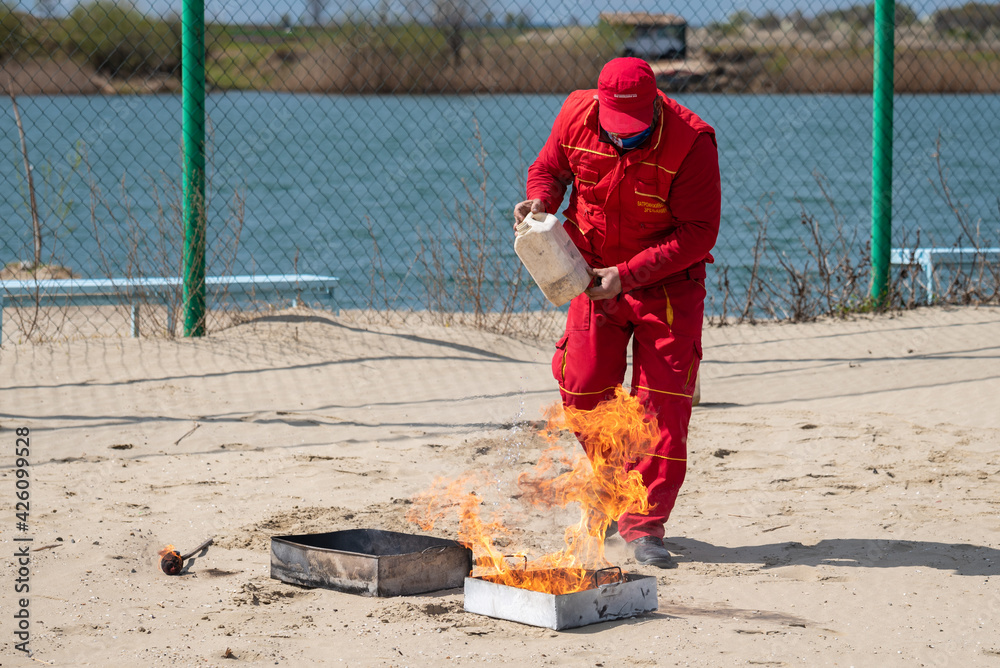 a man performs a firefighting exercise with a fire extinguisher, a large flame and black smoke