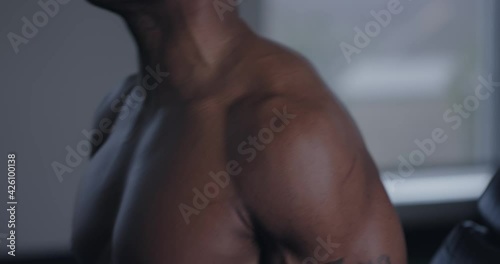 Closeup, Muscular arms and pecs of black man lifting weights, tilt up to face