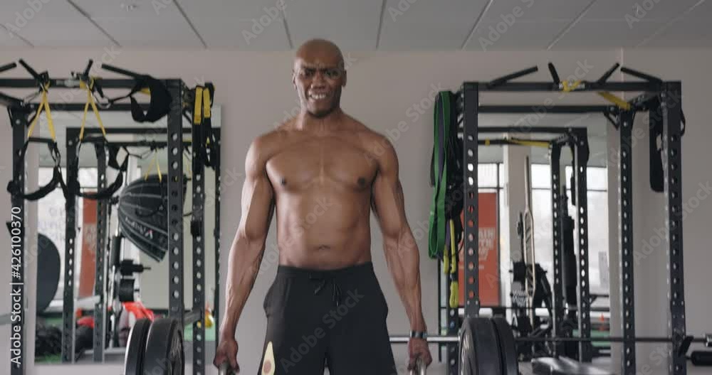 Muscular black man lifting trap bar weights in gym, follow tilt up and tilt down Muscular black man lifting trap bar weights in gym, follow tilt up and tilt down