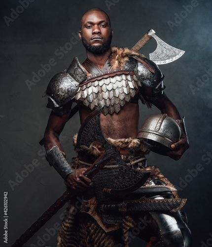 Handsome black skinned fighter with antique equipment and axe