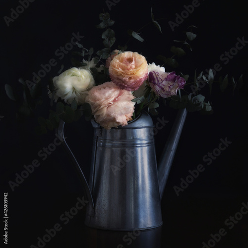 Watering can with flowers, looking like an old still life painting, vintage and shabby mood
