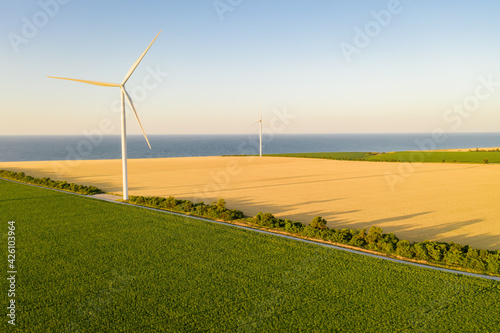 windmills on the seaside, wind turbine power generators at sunset.