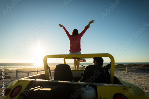 Happy caucasian couple on beach during sunset woman sitting on beach buggy man sitting in