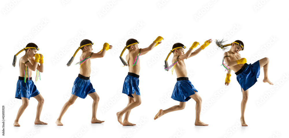 Obraz premium Little boy exercising thai boxing on white background. Fighter practicing, training in martial arts in action, motion. Evolution of movement, catching moment.