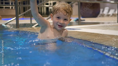 Little boy is playing in the water in the swimming pool.