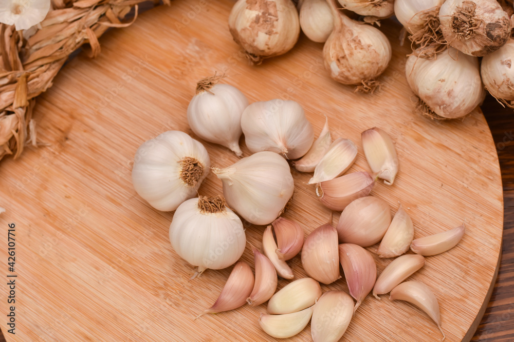 Garlic Cloves and Bulb on wooden cutting board. Garlic on wooden table background Garlic Cloves and Bulb on wooden cutting board. Garlic on wooden table background