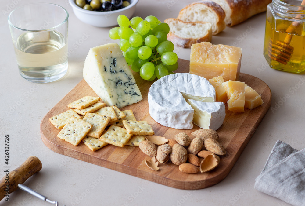 Cheese plate with cracker, almonds and grapes. Wine appetizer. Wine snack.