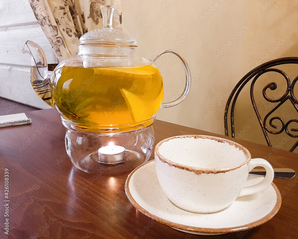 Herbal tea with fruit and rosemary in a glass teapot. A leisurely morning with a healthy drink.