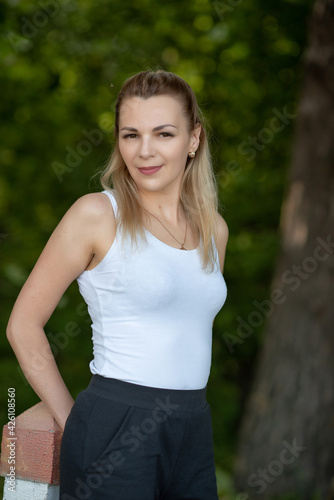 Portrait of a young beautiful blonde girl in a white T-shirt in the forest.